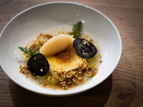 Dessert with sorbet, caramelized topping, crunchy nuts and black accents on a plate.