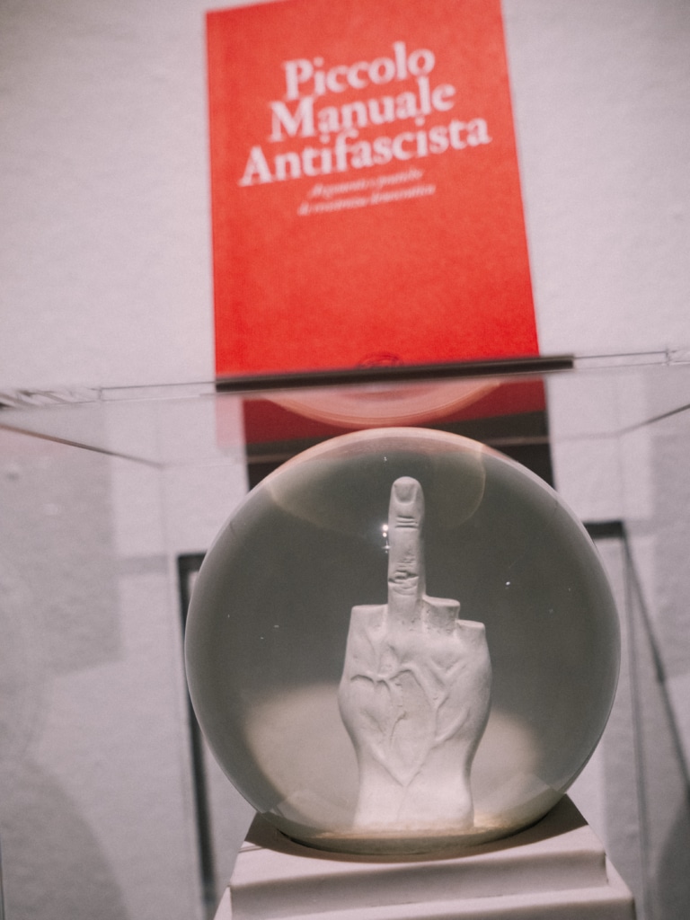 Artful provocation Ball with raised hand in front of red book in modern exhibition